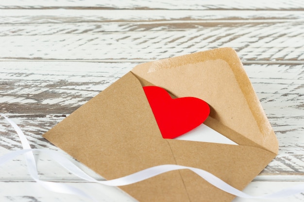 Love letter with paper heart on wooden background. Festive greeting card for St Valentines day.