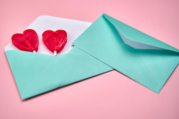 Love letter with two heartshaped red lollipops inside on a pink background