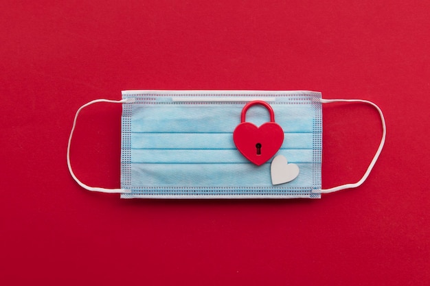 Love in lockdown red heart shaped valentine padlock on a coronavirus mask