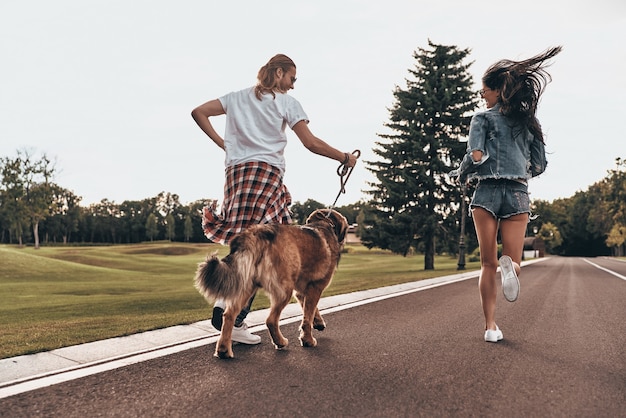 Love makes everything possible. Full length rear view of beautiful young couple running with their dog while spending time outdoors