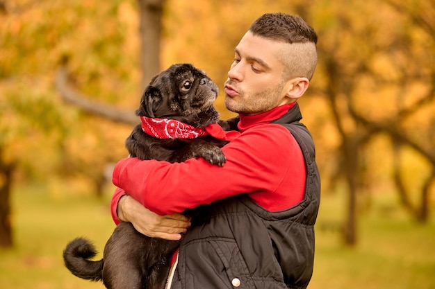 愛。公園に立って犬を抱きしめる男