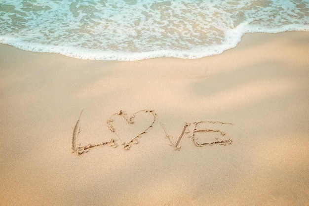 Love message hand writing on the sand beach