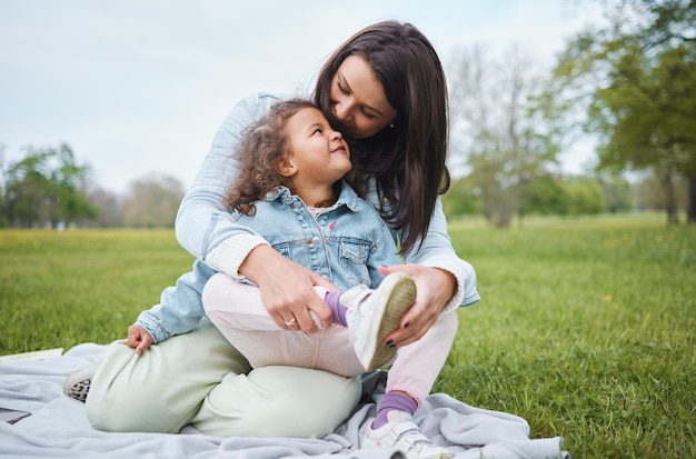 Love mother and girl on blanket at park having fun and bonding Care family and happy mom embrace with daughter at garden smiling and enjoying quality time together outdoors in nature on grass