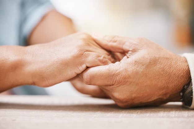 Love praying or old couple holding hands together in a Christian home in retirement with hope or faith Jesus religion or belief with a senior man and woman in prayer to god for spiritual bonding