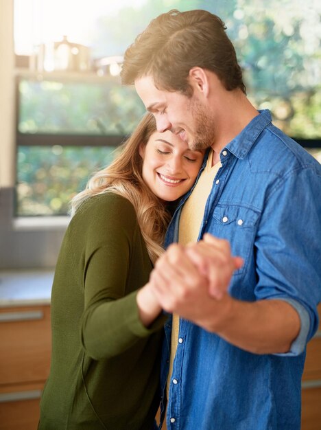 Foto l'amore mette il cuore in una casa inquadratura di una giovane coppia affettuosa che balla insieme mano nella mano nella loro cucina