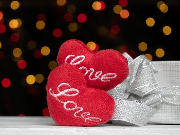 Love red heart shape and silver gift box on white wood with colourful bokeh