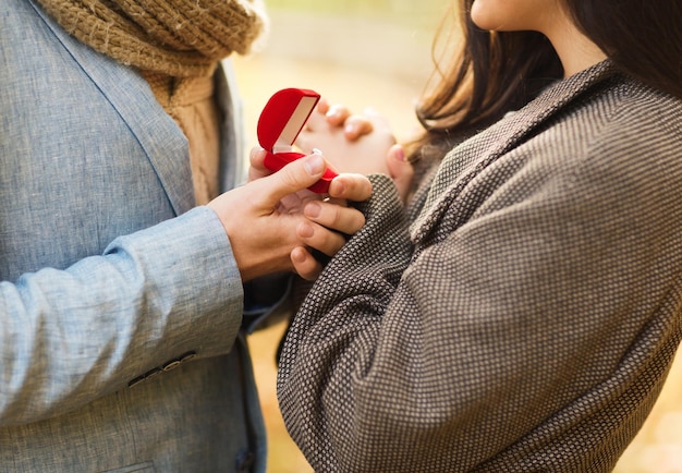 Concetto di amore, relazione, famiglia e persone - primo piano di coppia con confezione regalo rossa nel parco autunnale