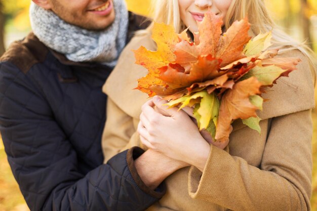 Photo love, relationship, family and people concept - close up of smiling couple with bunch of leaves hugging in autumn park