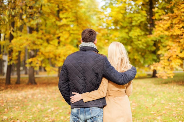 love, relationship, family and people concept - couple hugging in autumn park from back