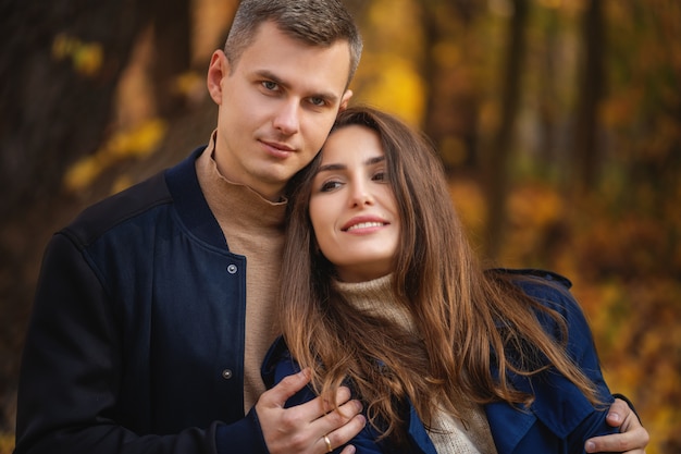 Love, relationship, family and people concept - smiling couple hugging in autumn park