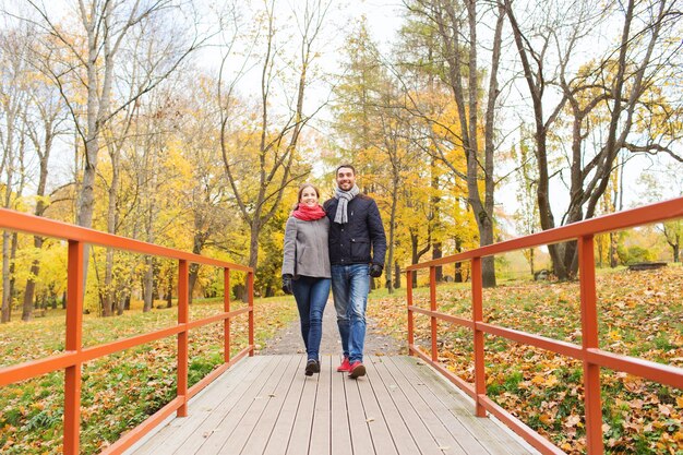 love, relationship, family, season and people concept - smiling couple hugging on bridge in autumn park