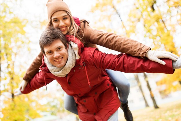 love, relationships, season and people concept - happy young couple having fun in autumn park