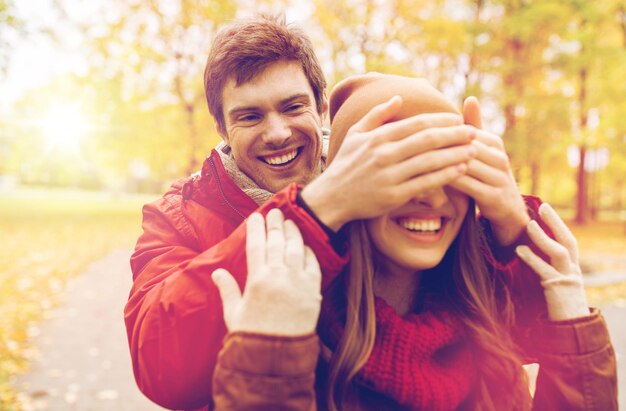 Foto amore, relazioni, stagioni e persone concetto - giovane coppia felice che si diverte nel parco d'autunno