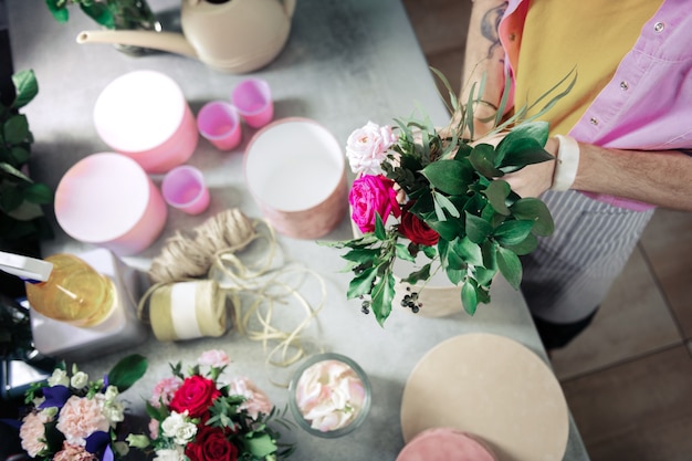 Love the result. Professional florist composing bouquet while using green plants