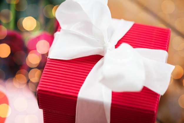 love, romance, valentines day and holidays concept - close up of red gift box with white bow