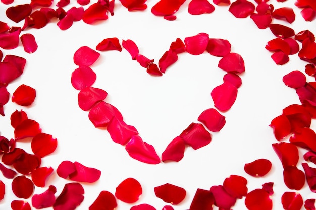 love, romance, valentines day and holidays concept - close up of red rose petals in heart shape