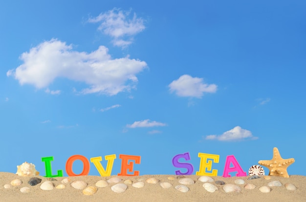 Photo love sea letters on a beach sand against the blue sky