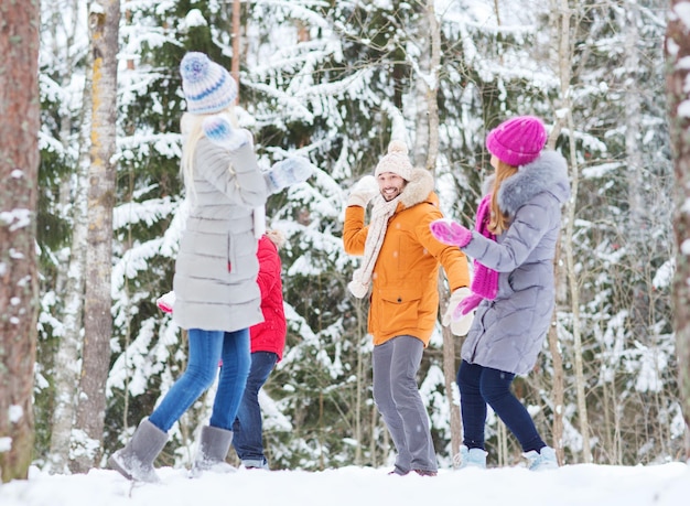 사랑, 계절, 우정, 엔터테인먼트, 그리고 사람들의 개념 - 행복한 남녀들이 겨울 숲에서 즐겁게 놀고 눈덩이를 하고 있습니다.