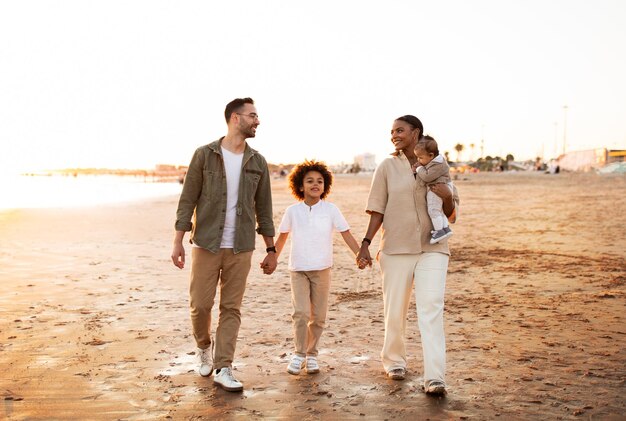 Love on the shoreline family walking on the beach with two sons holding hands and smiling enjoying