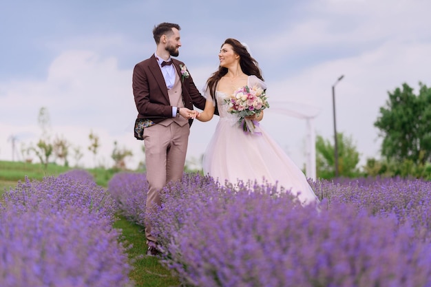 Foto storia d'amore delle coppie di spose che camminano nel prato di lavanda