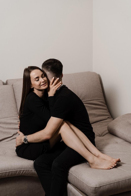 Love story of a couple spending time in cozy room at home Relationships feelings and tenderness in the family of men and girl Couple in love hugging and kissing on couch at home