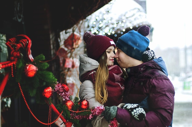 Love story of funny couple in snowy white city, park: young man, woman. Family winter holiday, date