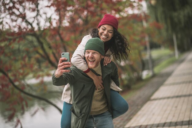 Love story. Smiling partners making emotional selfies in the autumn park