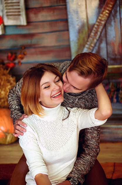 Love story of young happy, funny couple in studio, cozy home. Autumn decorations, orange pumpkins.