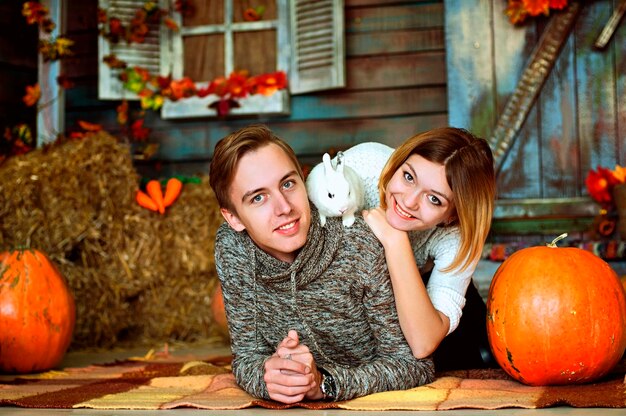 Love story of young happy, funny couple in studio, cozy home. Autumn decorations, orange pumpkins.