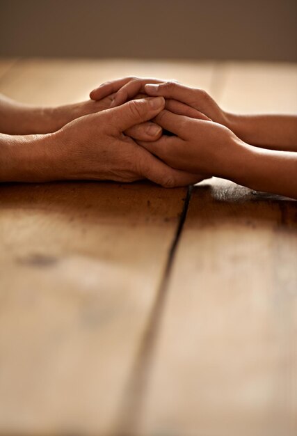 Foto sostegno d'amore e primo piano delle persone che si tengono per mano per il dolore speranza e simpatia dopo la perdita empatia di gratitudine e coppia che ha un momento intimo con affetto per l'unità fiducia e solidarietà sul tavolo