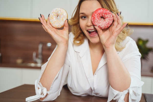 Love sweets. Delighted girl holding donuts and smiling a