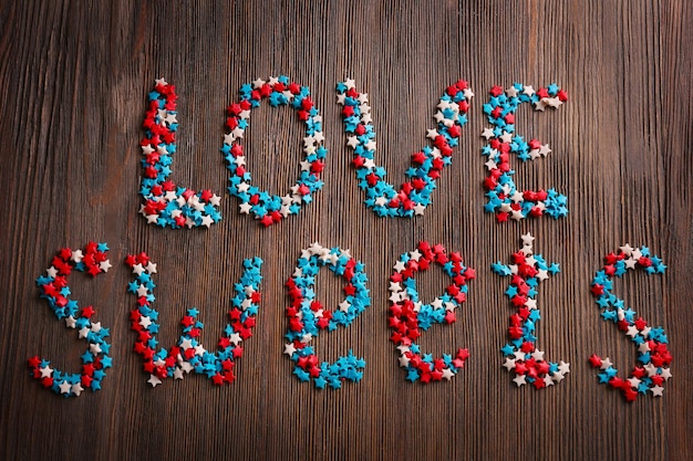 Love sweets inscription with candies on wooden background