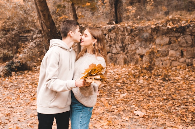 Love teenage couple posing outdoors kissing