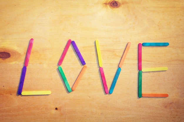 love text from colorful sticks on brown wooden background