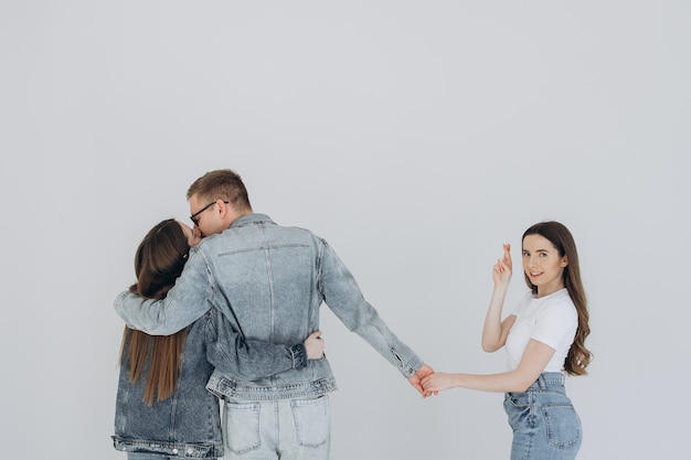 Love triangle Handsome man embrace his girlfriend while holding hands with another girl