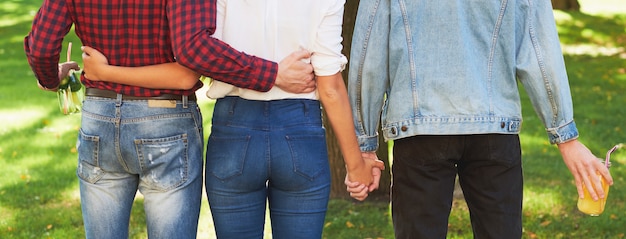 Foto triangolo amoroso. amicizia e gelosia giovanile. adulterio o poligamia. donna e due uomini che si tengono per mano