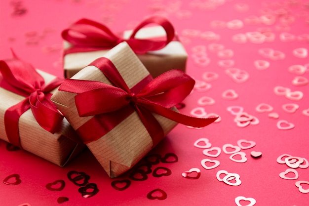 Love, Valentine's Day background. Gift box wrapped with kraft paper and red bow isolated on red background.