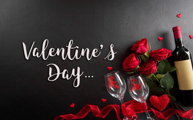Love and valentine\'s day concept made from champagne glasses\
wine red hearts rose and the text on black wooden background