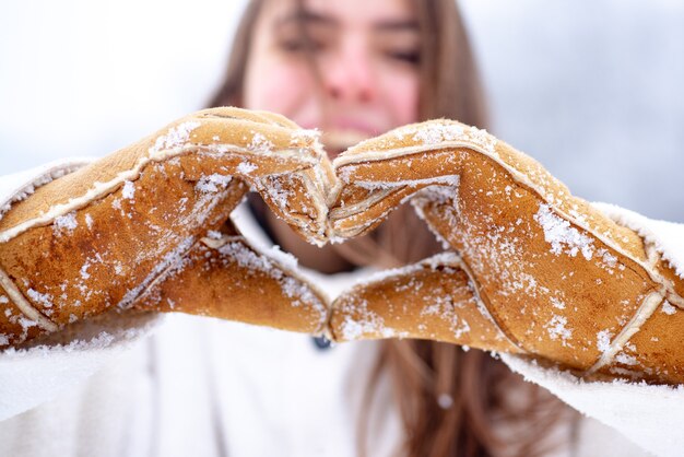 Love winter. Charity. Happy woman shows heart. Woman hands in winter gloves Heart symbol shaped