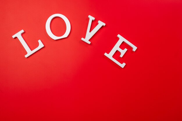 LOVE , wooden white letters on red background. Creative Valentine's Day