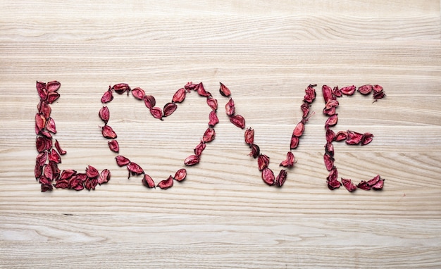 Foto parola d'amore e cuore fatto di petalo di rosa.