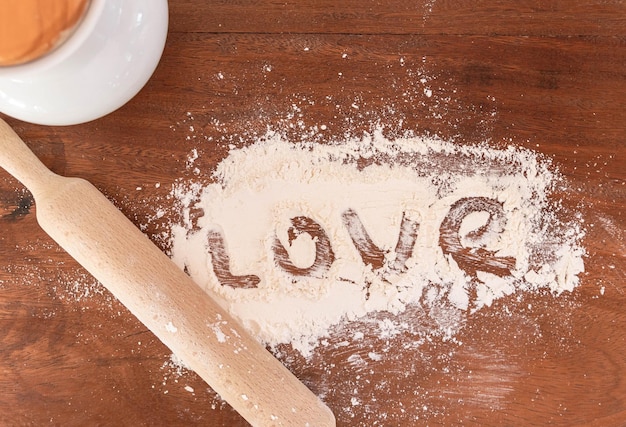 Love word written with flour on a wooden countertop