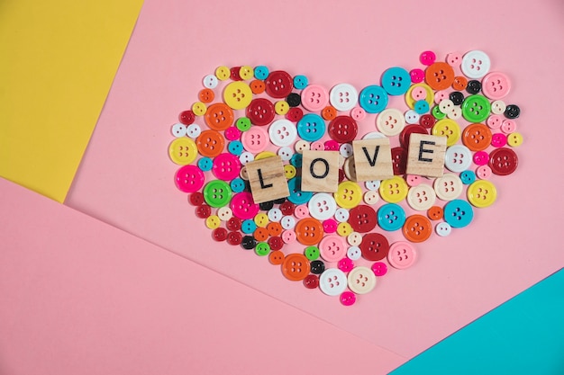 love word written on wooden block on colourful button in heart shape