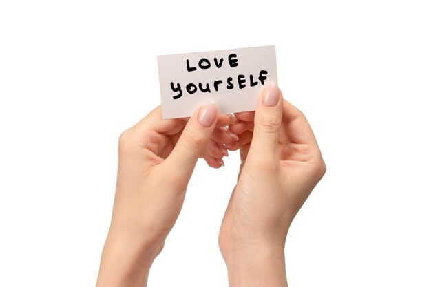 Love yourself text on a card in a woman hand isolated on a white background