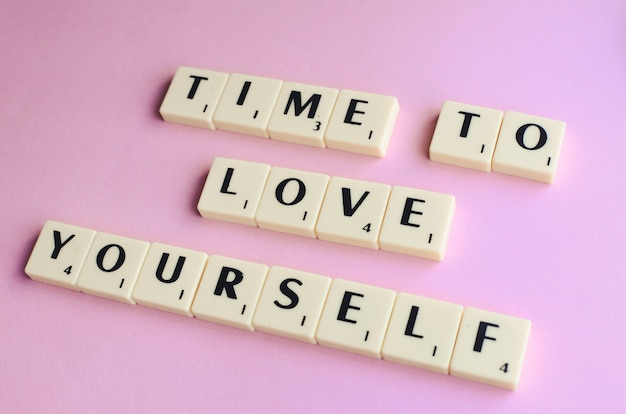 LOVE YOURSELF word on wooden cubes on a pink background