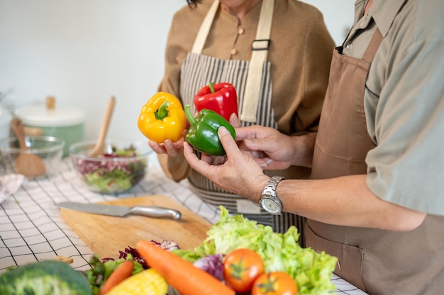 A lovely adult couple cooking in the kitchen together preparing fresh vegetables and ingredients