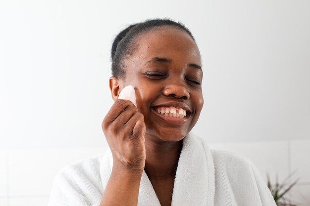 Lovely african girl massaging face with rose quartz gua sha