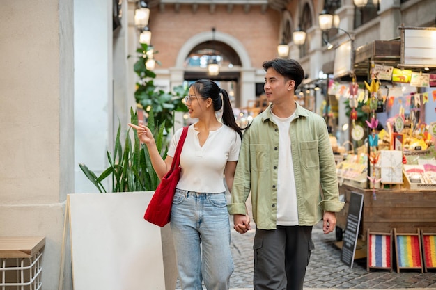 A lovely Asian couple are enjoying their time together as they walk through a market on a date