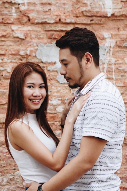 Lovely asian couple by a brick wall