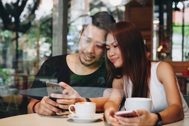 Coppie asiatiche adorabili che mangiano caffè